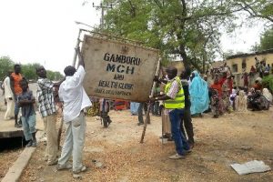 People raising a heath clinic sign in one of the devastated villages